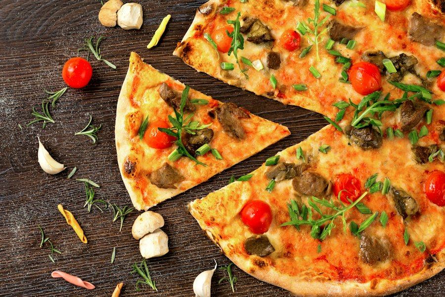 A freshly baked pizza being cut on a wooden board